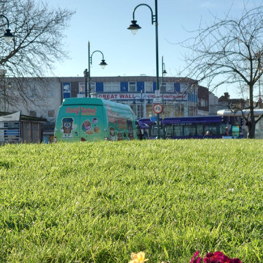 The Daily Grind Coffee Van parked behind a field surrounded by colorful flowers under a clear blue sky.